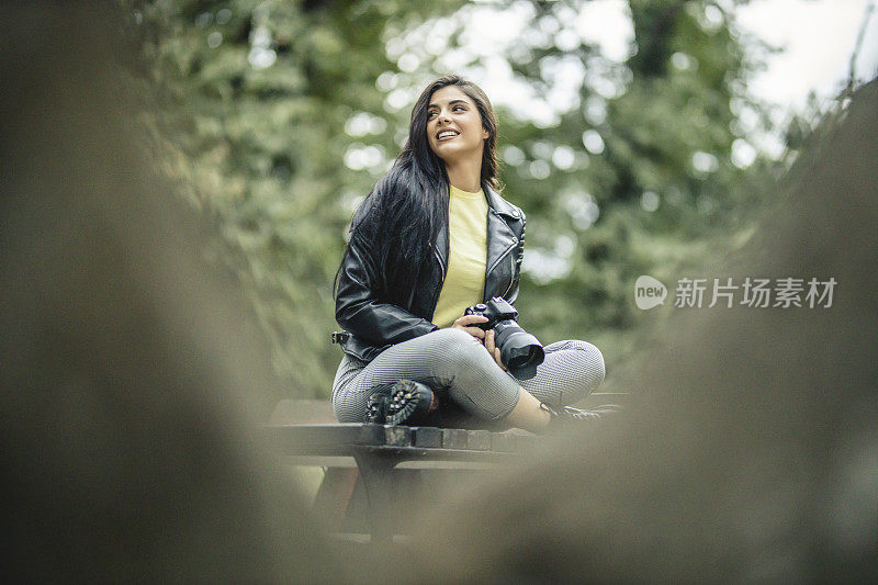 Young female photographer is taking a photo by her camera outdoors